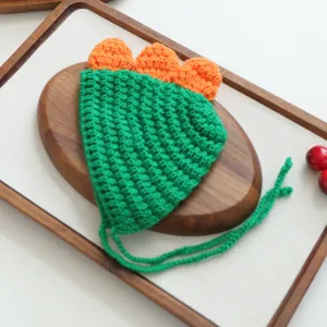 Détail du chapeau animal dinosaure au crochet, joli bonnet vert et orange tricoté fin.