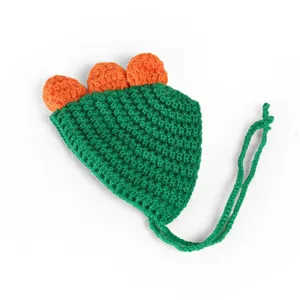 Vue détaillée du bonnet en crochet pour animal en forme de dinosaure vert avec épines et lanières.