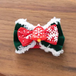 Nahaufnahme der weihnachtlichen Haarnadel für Haustiere mit roter Schleife und Glöckchen.