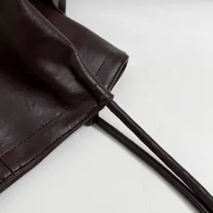 Dark brown leather bag close-up detail showcasing fine texture and stitching craftsmanship.