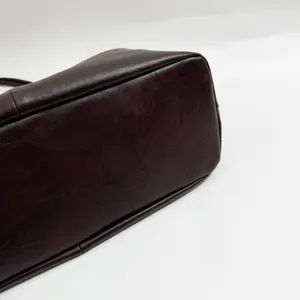 Dark brown oil wax leather tote bag bottom detail close-up, showing smooth texture.