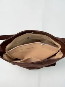 Detailed view of brown suede tote bag interior with multiple zipper compartments and lining.