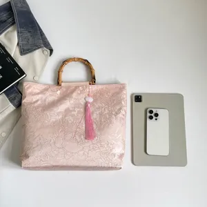 Elegante rosa Jacquard Handtasche mit natürlichem Bambusgriff und filigranem Quasten-Detail.
