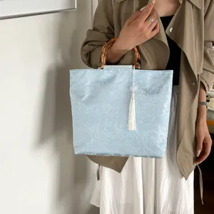 Detailansicht der Tasche im chinesischen Stil, hellblauer Blumenstoff mit Bambusgriff und Quaste.