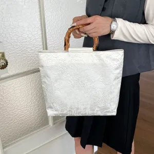 Nahaufnahme der eleganten weißen Leinentasche mit einem einzigartigen Bambus-Tragegriff.