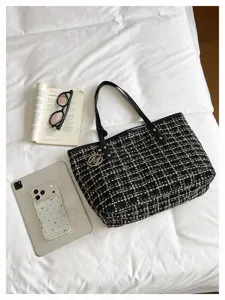 Gedetailleerd overzicht van de zwart-witte tweed shopper op een wit laken met accessoires.