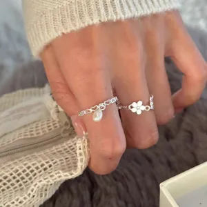 Gros plan détaillé des bagues en argent avec cœur creux, perle pendante et joli motif de fleur.
