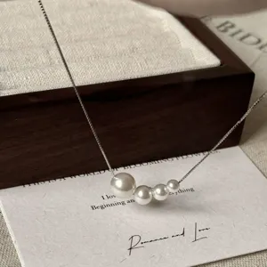 Gros plan détail de chaîne en argent avec pendentifs perlés dégradés, vitrine de bijoux élégante.