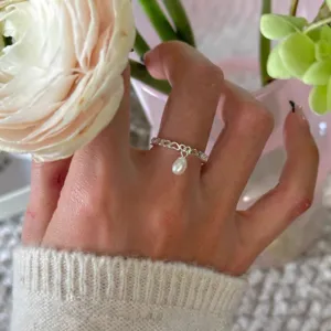 Détail de bague cœur en argent sterling avec pendentif perle délicat et style minimaliste.