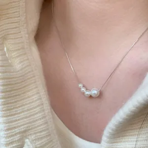 Gros plan détaillé d'un collier en chaîne argentée fine avec pendentif en perles dégradées.
