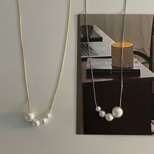Vue rapprochée en gros plan des colliers pendentifs asymétriques en or et argent de luxe.