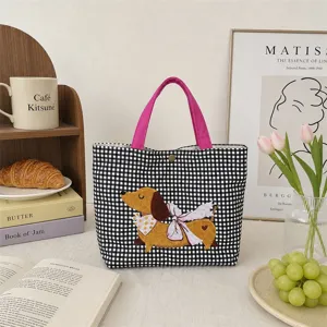 Nahaufnahme der schwarz-weiß karierten Canvas-Tragetasche mit gesticktem Dackel-Motiv.