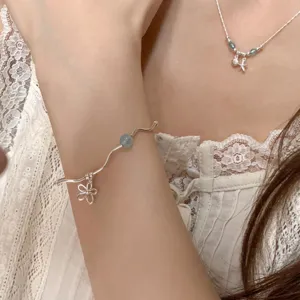Gros plan sur le bracelet en argent sterling ondulé avec perle aigue-marine et détail de fleur.