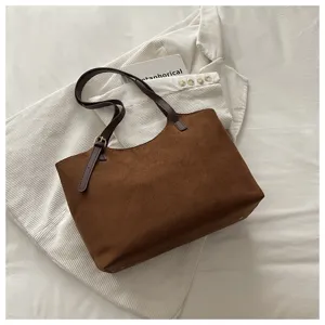 Dettaglio borsa shopper marrone scamosciata con texture morbida e manici scuri eleganti.