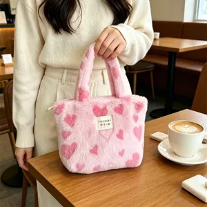 Vista dettagliata della graziosa borsa shopper in peluche rosa con stampe a cuore e manici.