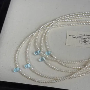 Collier de perles blanches multibrins délicat avec pendentifs gemmes bleus en gros plan.