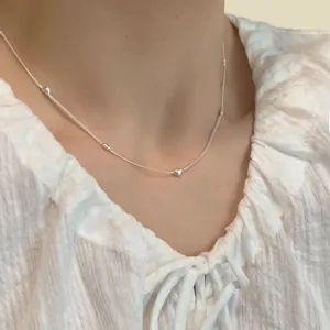 Gros plan detaille d'un collier de chaine en argent sterling delicat avec des mini coeurs.