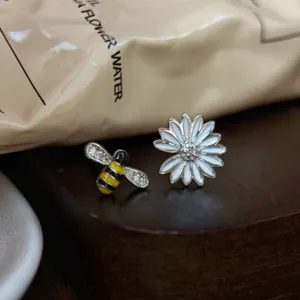 Vue détaillée de boucles d'oreilles asymétriques abeille et marguerite en argent S925 avec émail.