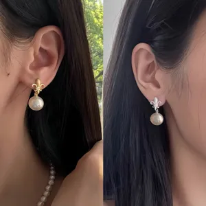 Gros plan détaillé des boucles d'oreilles perle fleur de lys en argent S925 sur modèle.