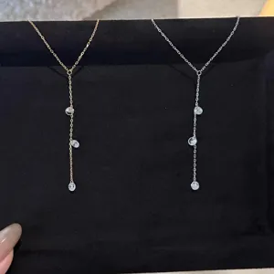 Vue detaillee de magnifiques et elegants colliers pendentifs Y bicolores et pierres.