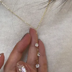 Gros plan détaillé du collier ras-de-cou doré en forme de Y avec des pierres scintillantes.