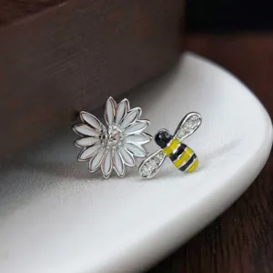 Gros plan de boucles d'oreilles asymétriques abeille et marguerite en argent S925 émail.