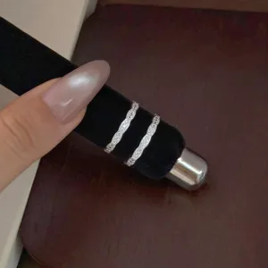 Vue détaillée d'un double anneau ondulé en argent, pierres scintillantes, accessoire élégant.