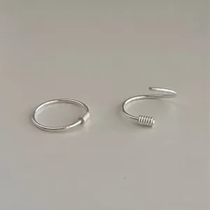 Vue de détail de boucles d'oreilles créoles argentées minimalistes, texture spiralée et fini lisse.