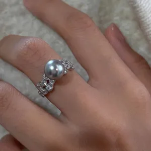 Gros plan d'une bague en argent sterling avec une perle grise et des zircons brillants.