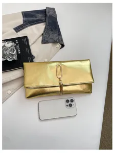 Pochette enveloppe métallisée dorée avec anneau élégant et détail de pompon pour un superbe look chic.