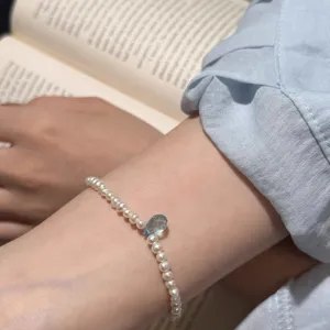 Gros plan détaillé d'un délicat bracelet de perles et de pierres précieuses bleues.