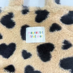 Dettaglio del tessuto della borsa in peluche morbido con stampa a cuore graziosa.