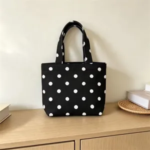Detailed close-up shot of the black and white polka dot canvas tote bag on a cozy wooden desk.