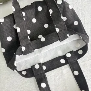 Detail shot of a black and white polka dot mini canvas tote bag with sturdy double handles.