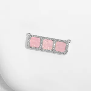 Detailaufnahme eines rechteckigen Kupfer-Verbinders mit Zirkonia und drei rosa Einsätzen.
