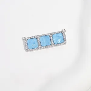 Detailansicht eines glitzernden Zirkonia-Verbinderanhängers mit drei blauen Muscheleinsätzen.
