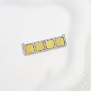 Detailed view of a rectangular brass pendant with cubic zirconia and yellow grid stones.