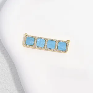 Gold-toned brass connector pendant featuring four blue square insets and sparkling cubic zirconia.