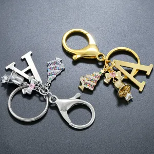 Close-up detail of rhinestone Christmas tree and alphabet keychain charms in gold and silver.
