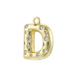 Dettaglio del ciondolo con lettera D in rame dorato e zirconi per creazione di gioielli.