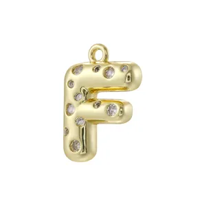 Primo piano di un ciondolo con lettera F 3D gonfia in rame placcato oro con scintillanti pietre di zircone.