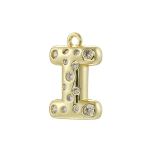 Primo piano di un ciondolo a lettera I gonfia placcato in oro adornato con pietre di zirconio cubico.