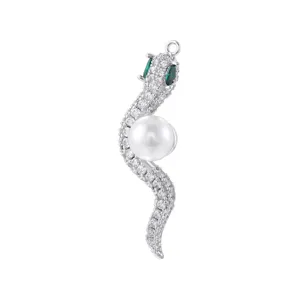 Close-up detail of silver tone snake pendant paved with micro zircons, green eyes and pearl.