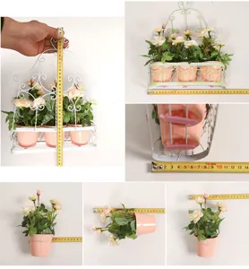 Wall mounted iron flower basket with pink plastic pots and artificial roses for home decor
