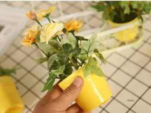 Mini artificial rose potted plant in yellow plastic pot, perfect home decor desktop ornament.
