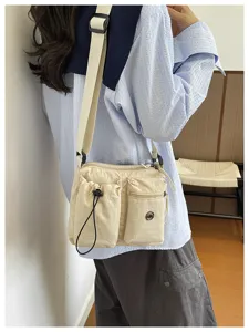 Detail view of the multi-pocket nylon crossbody bag worn by model in casual setting.