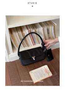 Black shoulder bag detail view, classic minimalist design with metallic lock and mini pouch.