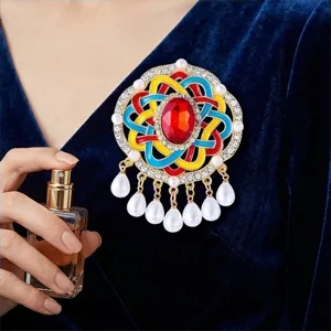 Gedetailleerd overzicht van een kleurrijke vintage broche met parelkwastjes en strass.