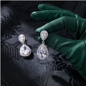 Primo piano di luminosi orecchini pendenti in zirconia cubica con dettaglio halo.