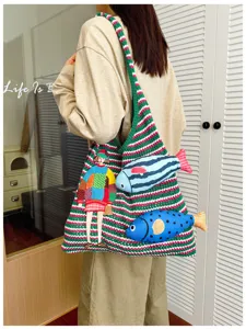 Close-up detail of knitted striped shoulder bag featuring girl embroidery and 3D fish.